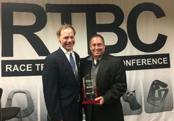 Charlotte Motor Speedway Executive Director of Operations Shaun Johnson, right, accepts the speedway's "Outstanding Facility of the Year" award from National Speedway Directory Publisher, Director and President Timothy Frost during the Race Track Business Conference on Wednesday in Indianapolis.