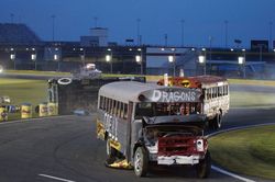 School buses driven by area principals go by as the overturned bus of W.M. Irvin Elementary's Drew Fitzgerald sits on its side during Bojangles' Summer Shootout action on Tuesday.